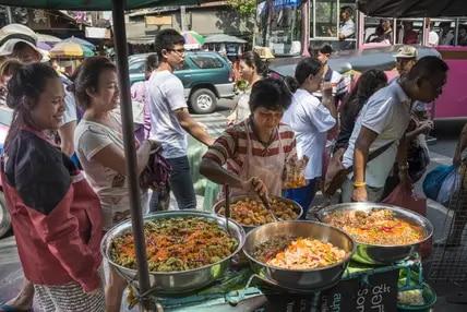 Authentische Thai-Küche aus heißen Woks: Straßenverkäuferinnen und Straßenverkäufer bieten in Bangkok an fast jeder Ecke frische Gerichte an - hier etwa in Chinatown. 